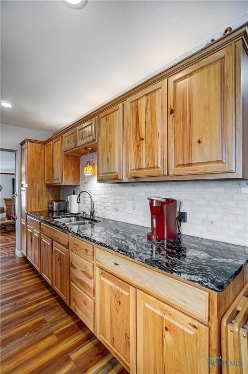 kitchen with dark stone counters, sink, dark hardwood / wood-style flooring, and decorative backsplash