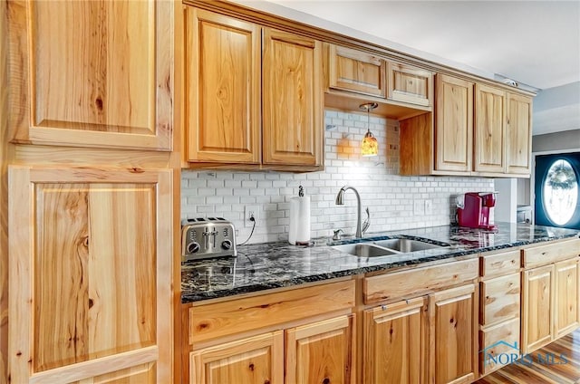 kitchen with hanging light fixtures, dark stone countertops, sink, and tasteful backsplash