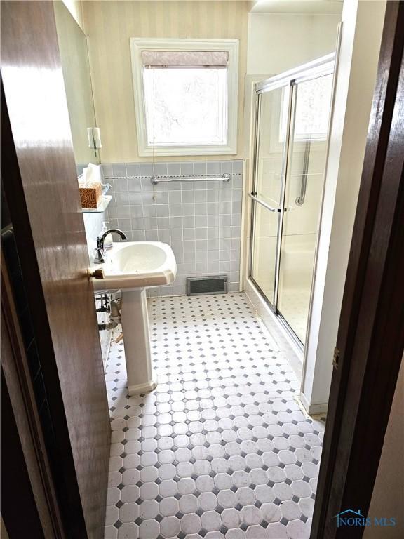 bathroom with an enclosed shower and tile walls