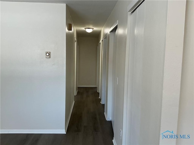 corridor with dark wood-style floors and baseboards