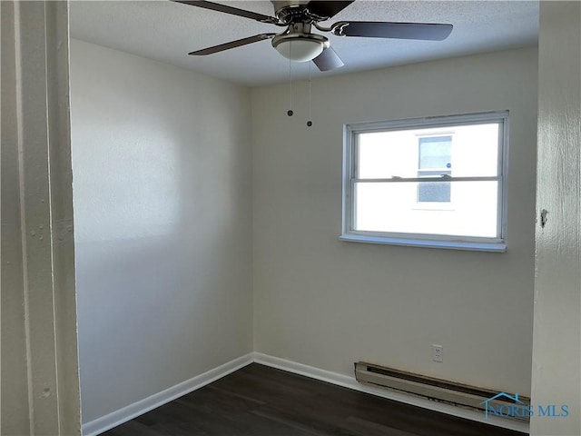 empty room with a baseboard heating unit, dark wood-type flooring, a ceiling fan, and baseboards