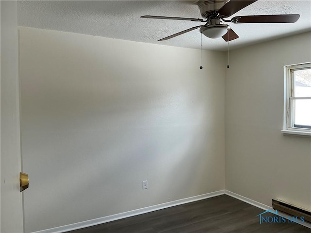 spare room with dark wood-style flooring, a baseboard radiator, a ceiling fan, a textured ceiling, and baseboards