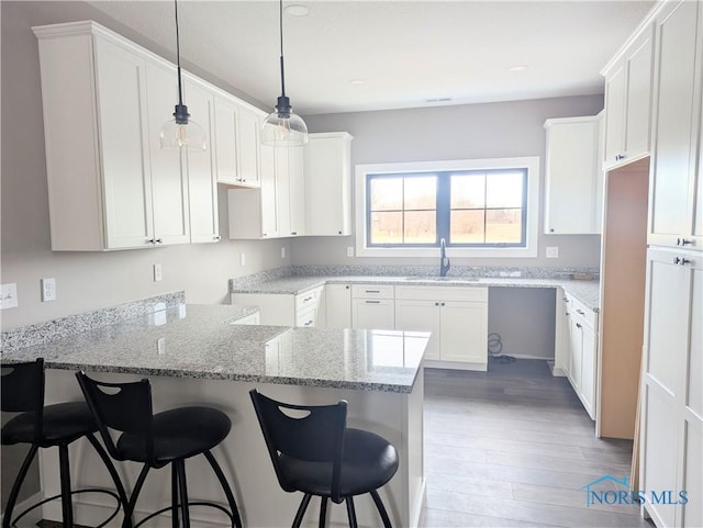 kitchen with white cabinetry, a kitchen bar, and light stone countertops