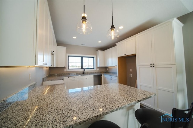 kitchen with decorative light fixtures, white cabinets, a kitchen bar, and kitchen peninsula