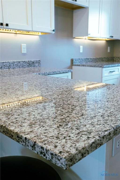 kitchen featuring white cabinetry, light stone counters, and kitchen peninsula