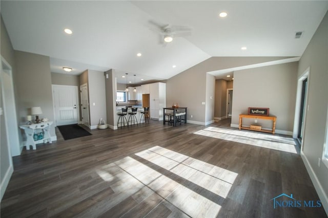 unfurnished living room featuring ceiling fan, dark hardwood / wood-style flooring, and vaulted ceiling