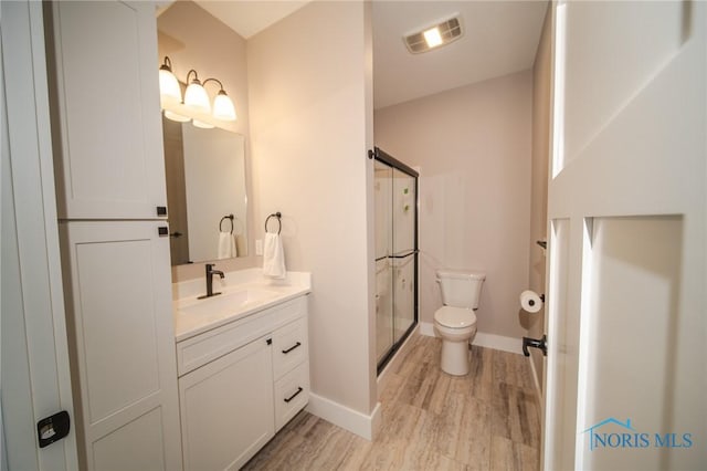 bathroom featuring vanity, hardwood / wood-style floors, a shower with door, and toilet