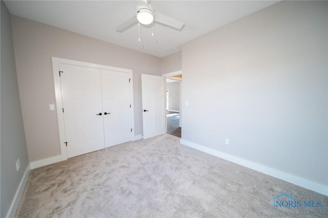 unfurnished bedroom featuring ceiling fan, a closet, and light carpet