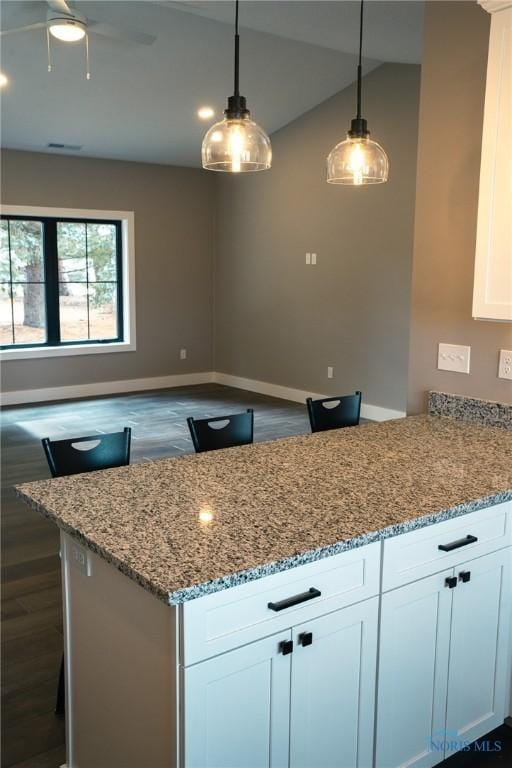 kitchen with white cabinetry, light stone countertops, dark wood-type flooring, and decorative light fixtures