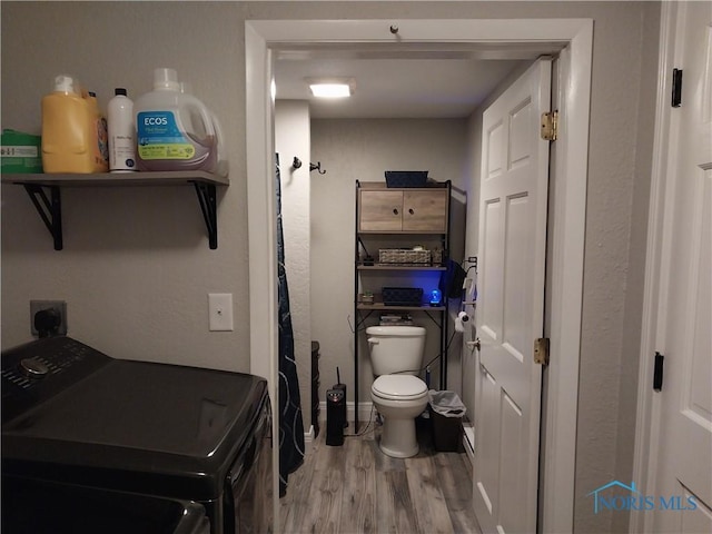 bathroom featuring separate washer and dryer, wood-type flooring, and toilet