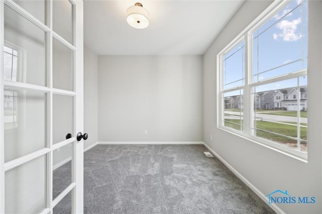 carpeted empty room with french doors and a healthy amount of sunlight