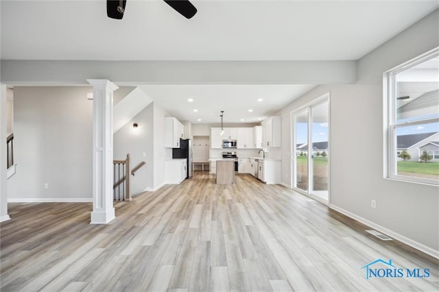 unfurnished living room with decorative columns, ceiling fan, and light hardwood / wood-style flooring