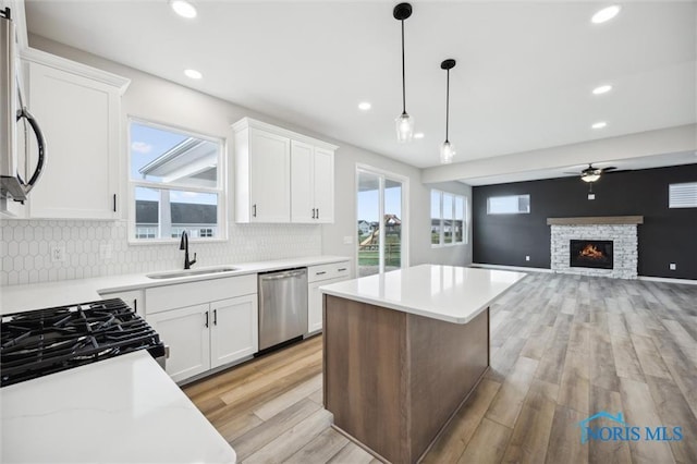 kitchen featuring sink, decorative light fixtures, a center island, appliances with stainless steel finishes, and white cabinets