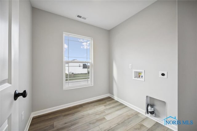 clothes washing area with hookup for a washing machine, electric dryer hookup, and hardwood / wood-style floors