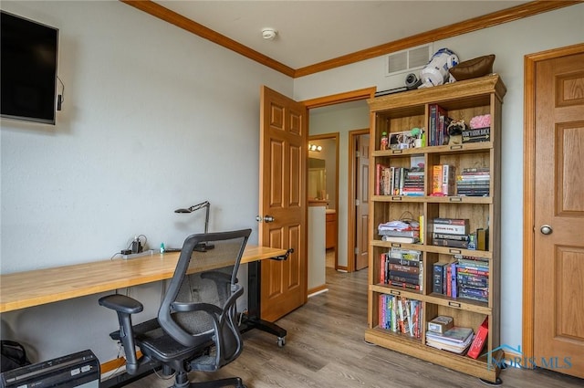 home office with crown molding and light hardwood / wood-style floors