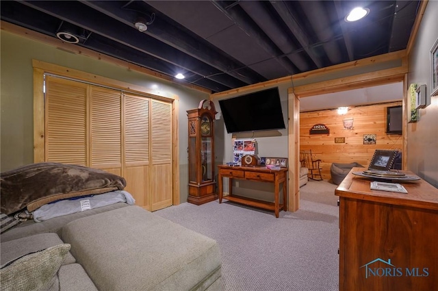 bedroom featuring a closet, light carpet, and wood walls