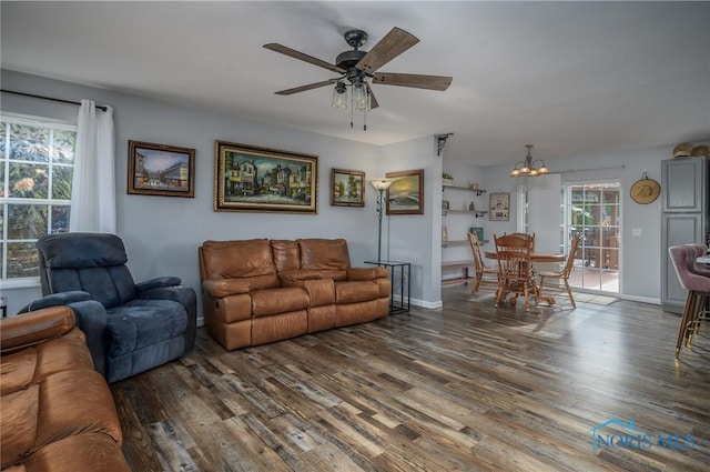 living room with ceiling fan with notable chandelier and dark hardwood / wood-style flooring