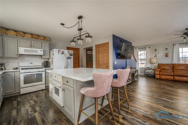 kitchen with white appliances, decorative light fixtures, gray cabinets, and a kitchen island