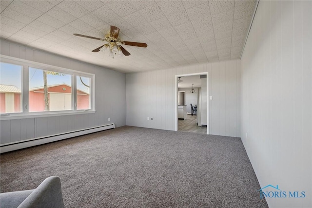 carpeted spare room featuring a baseboard radiator and ceiling fan