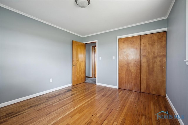 unfurnished bedroom featuring crown molding, light hardwood / wood-style flooring, and a closet