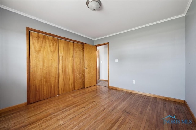 unfurnished bedroom with crown molding, light hardwood / wood-style floors, and a closet