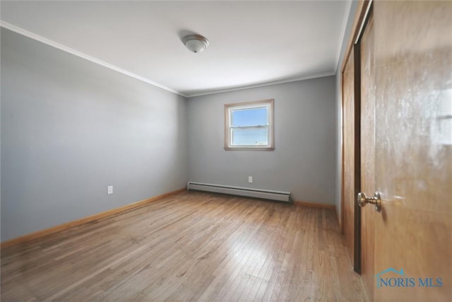 spare room featuring hardwood / wood-style flooring, ornamental molding, and baseboard heating