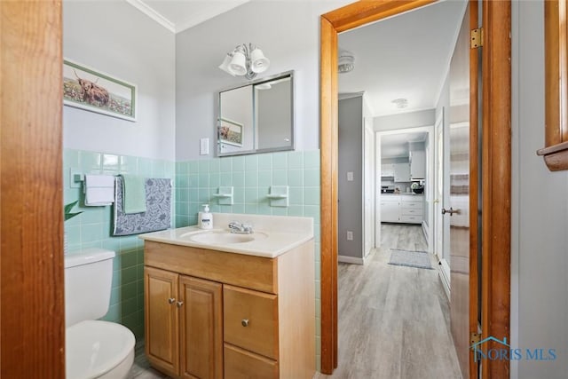 bathroom with tile walls, vanity, wood-type flooring, ornamental molding, and toilet