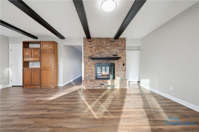 unfurnished living room with a fireplace, dark wood-type flooring, and beamed ceiling