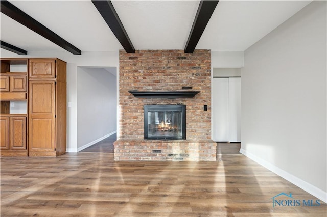 unfurnished living room featuring beam ceiling, hardwood / wood-style flooring, and a fireplace