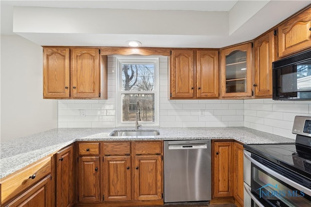 kitchen featuring tasteful backsplash, stainless steel appliances, light stone countertops, and sink