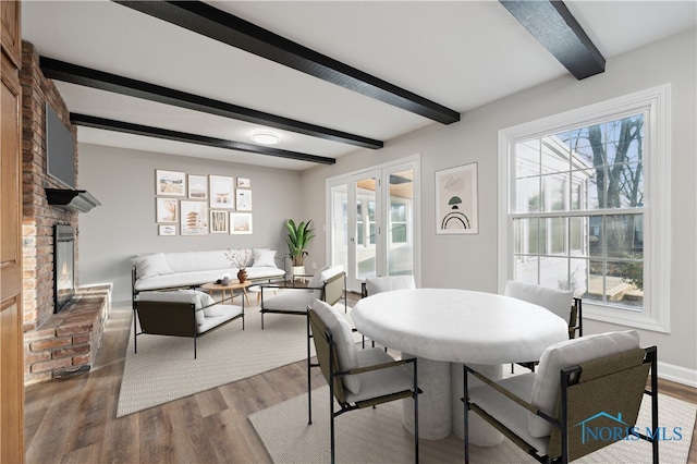 dining area with french doors, plenty of natural light, hardwood / wood-style floors, and a brick fireplace