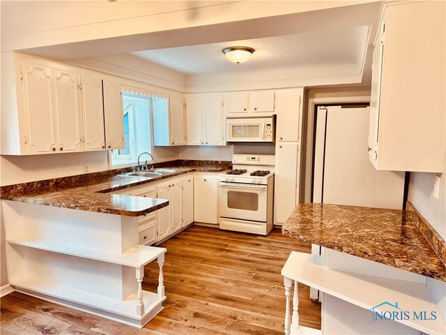 kitchen with white cabinetry, sink, white appliances, and light hardwood / wood-style floors