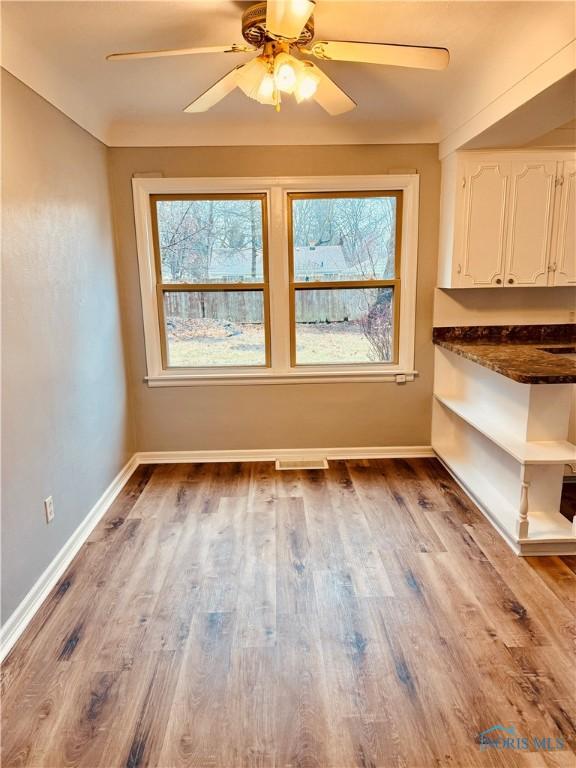 interior space with a ceiling fan, baseboards, and wood finished floors