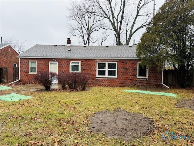 rear view of property featuring brick siding, fence, a chimney, and a lawn