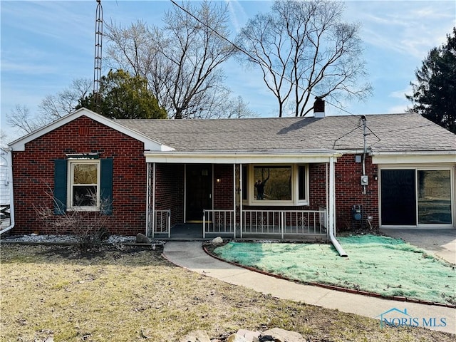 single story home featuring a shingled roof, a porch, brick siding, and a chimney