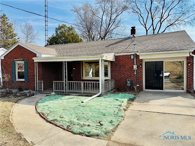 ranch-style home with brick siding, covered porch, a chimney, and roof with shingles