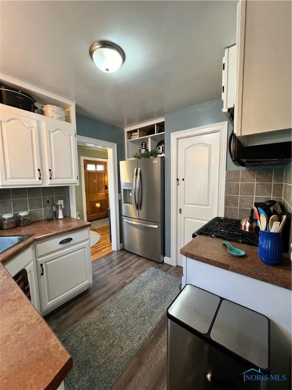 kitchen featuring stainless steel refrigerator with ice dispenser, white cabinetry, dark hardwood / wood-style flooring, and backsplash