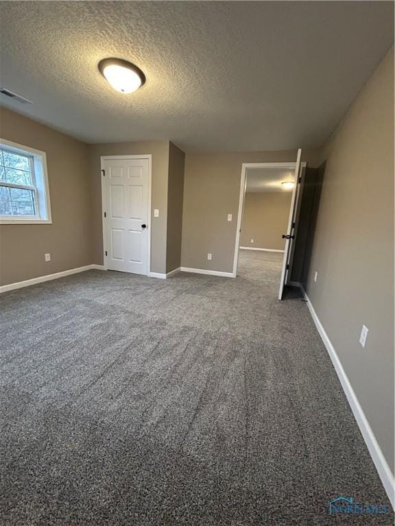 unfurnished bedroom featuring dark colored carpet and a textured ceiling