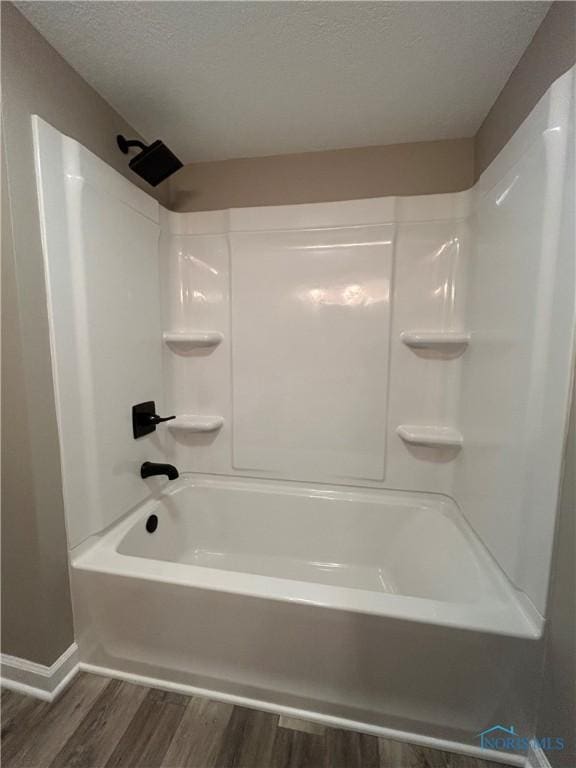 bathroom with hardwood / wood-style flooring, bathtub / shower combination, and a textured ceiling