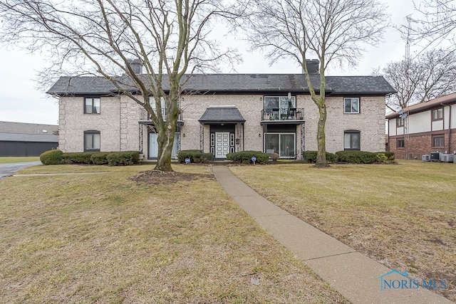 view of front of home with a balcony, a front yard, and central AC unit