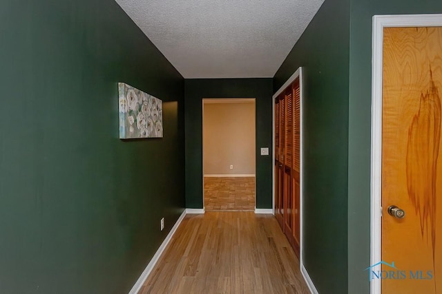 hall featuring a textured ceiling and light hardwood / wood-style flooring