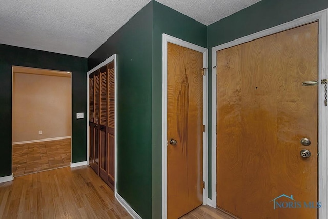 hall featuring wood-type flooring and a textured ceiling