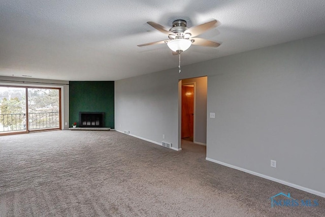 unfurnished living room with ceiling fan, a fireplace, carpet floors, and a textured ceiling