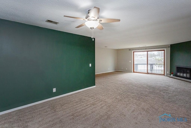 unfurnished living room featuring ceiling fan, carpet, a fireplace, and a textured ceiling