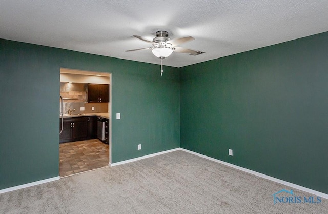 carpeted empty room featuring sink, a textured ceiling, and ceiling fan