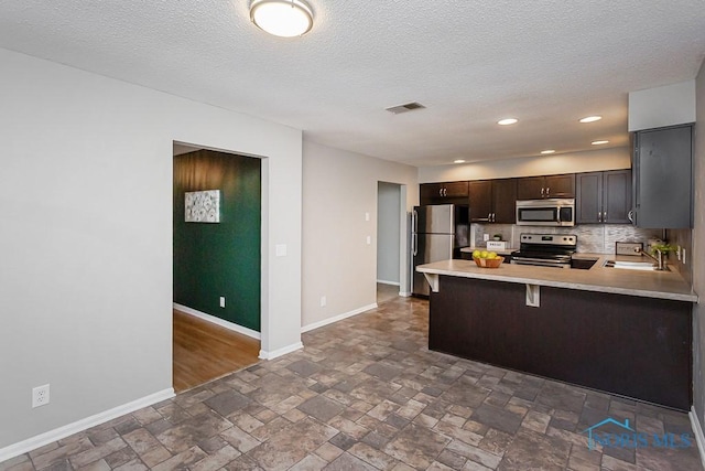 kitchen with sink, a breakfast bar area, decorative backsplash, kitchen peninsula, and stainless steel appliances