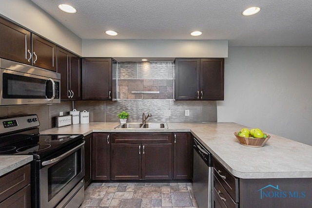 kitchen featuring sink, dark brown cabinets, kitchen peninsula, stainless steel appliances, and backsplash