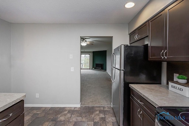 kitchen with dark brown cabinetry, electric range oven, a textured ceiling, stainless steel refrigerator, and ceiling fan