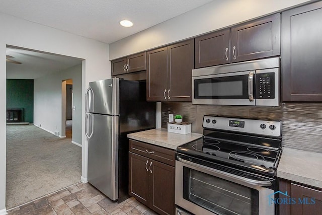 kitchen featuring dark brown cabinetry, light carpet, and stainless steel appliances