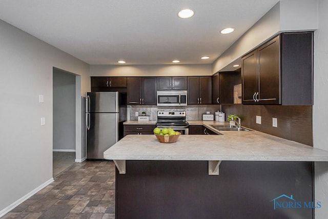 kitchen with sink, dark brown cabinets, kitchen peninsula, and appliances with stainless steel finishes